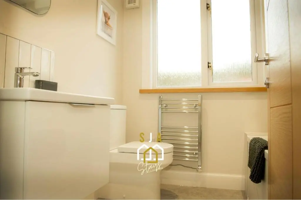 a bathroom with a white toilet and a window at Beachside Cottage - SJA Stays - Modern 3 Bedroom House in Cullen