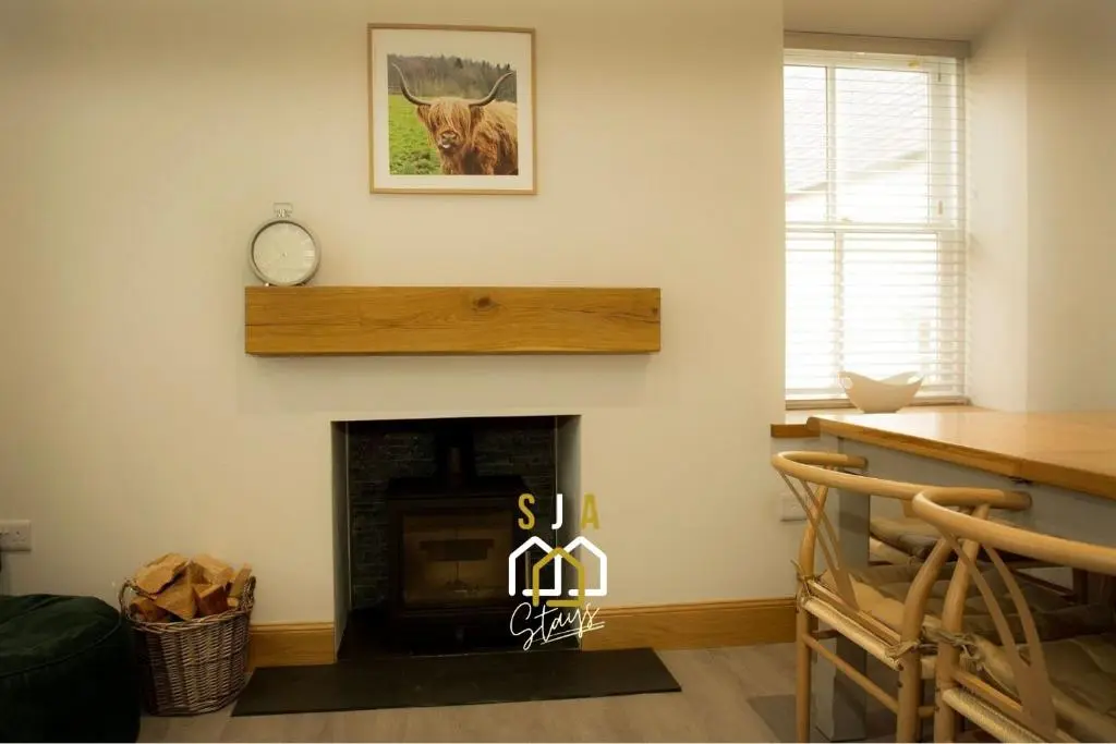 a living room with a fireplace with a clock on the wall at Beachside Cottage - SJA Stays - Modern 3 Bedroom House in Cullen