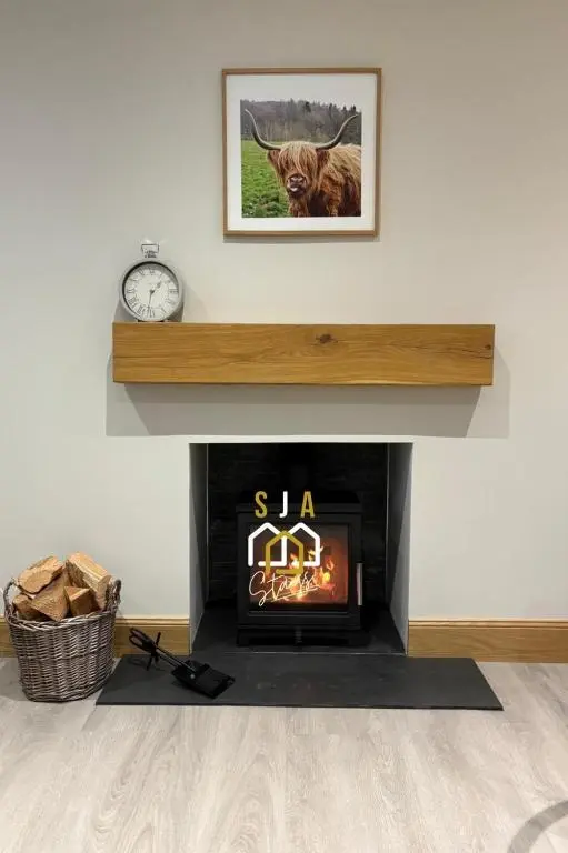 a living room with a fireplace with a clock at Beachside Cottage - SJA Stays - Modern 3 Bedroom House in Cullen