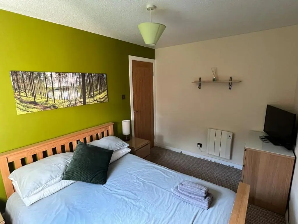 a bedroom with a bed with a green wall at 26 Two bedroom apt with private garden in Culloden