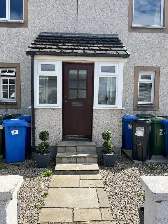 a house with a brown door and some trash cans at 26 Two bedroom apt with private garden in Culloden