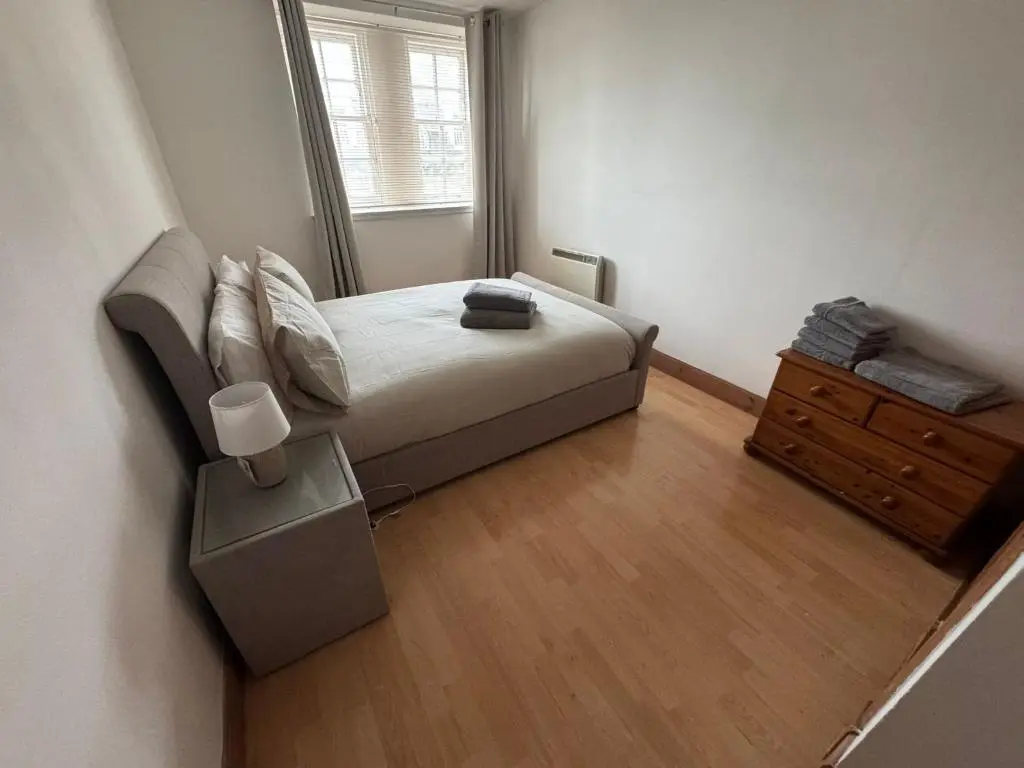 a small bedroom with a bed and a dresser at Church Street Apartment in Inverness