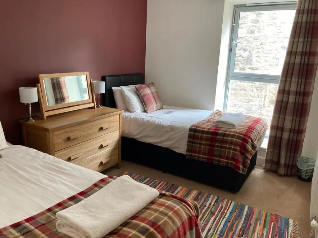 a bedroom with two beds and a mirror and a window at Raven Wing 17 - Aonach Mor in Fort Augustus