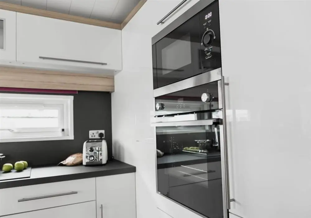 a kitchen with a stainless steel oven and white cabinets at Loch Ness Highland Resort in Fort Augustus