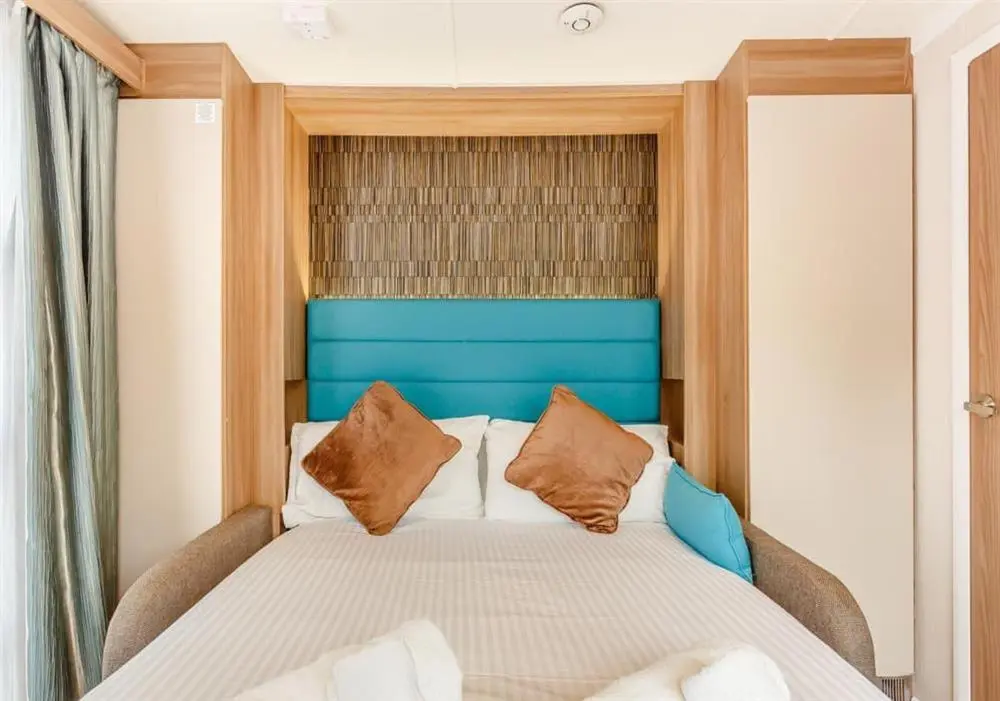 a bedroom with a large bed with a blue headboard at Loch Ness Highland Resort in Fort Augustus