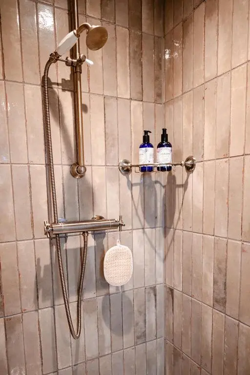 a bathroom with a shower with two bottles of soap at Garradh Cottage - Seasgair Lodges in Kincraig