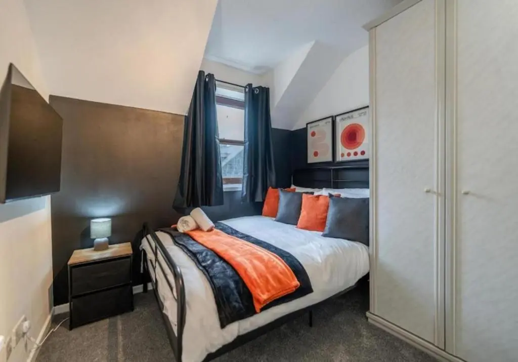 a bedroom with a bed with orange and blue pillows at Bright & Spacious 2BR Fraserburgh for Work & Family Stays in Fraserburgh