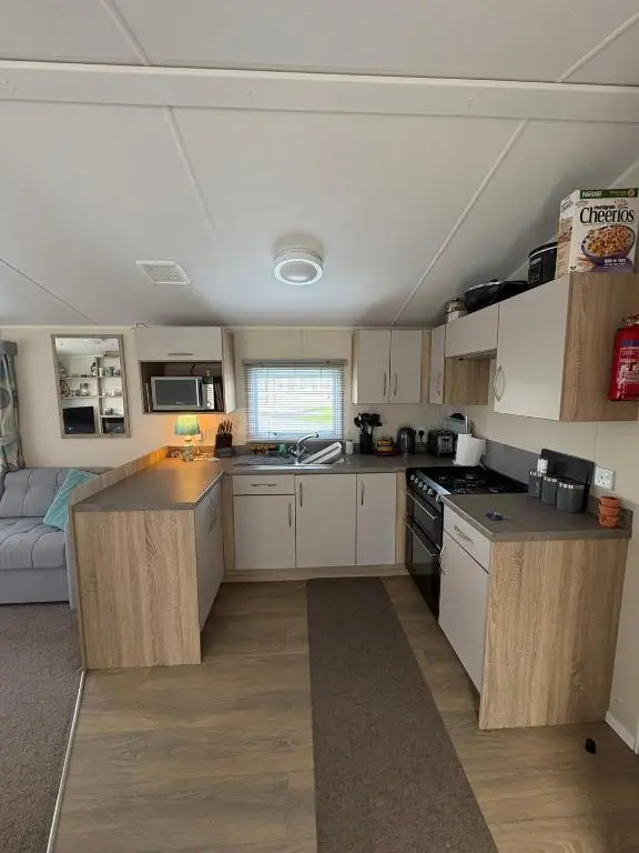 a small kitchen with white cabinets and a couch at Pebble Cove 74 in Lossiemouth