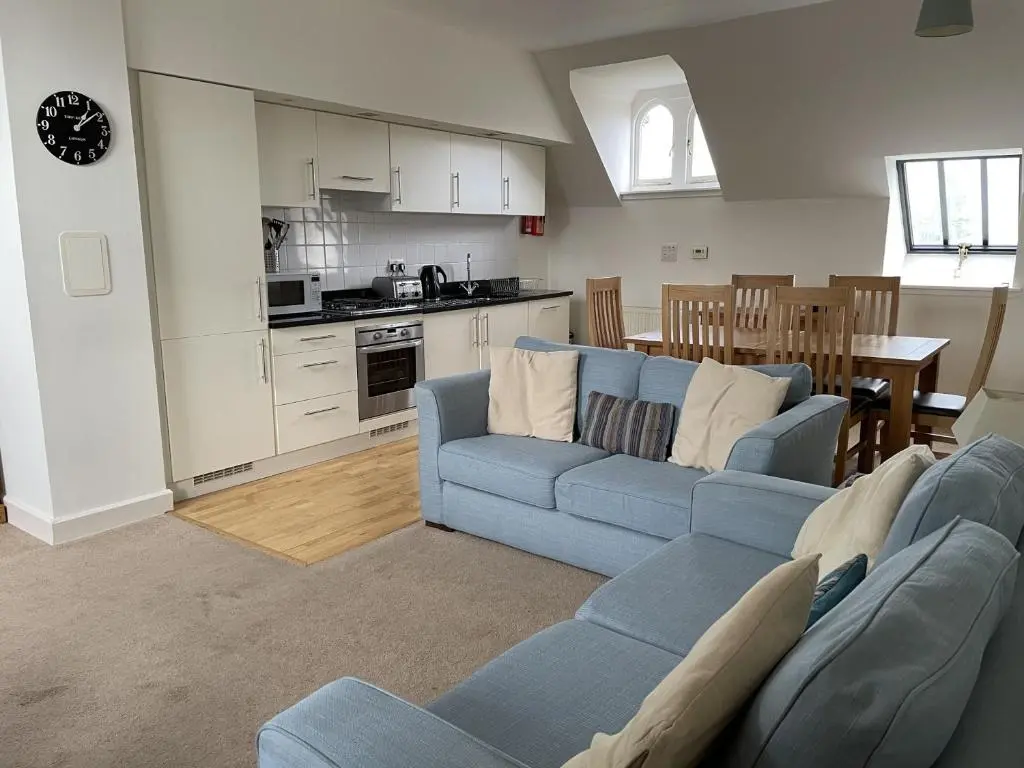 a living room with a blue couch and a kitchen at Monastery 17 in Fort Augustus