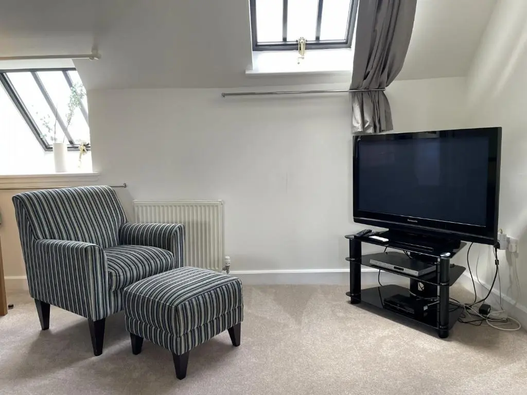 a living room with a chair and a flat screen tv at Monastery 17 in Fort Augustus