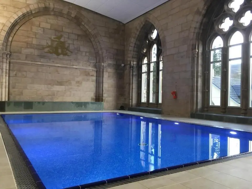 a large swimming pool with blue water in a building at Monastery 17 in Fort Augustus