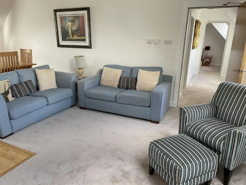 a living room with a blue couch and two chairs at Monastery 17 in Fort Augustus