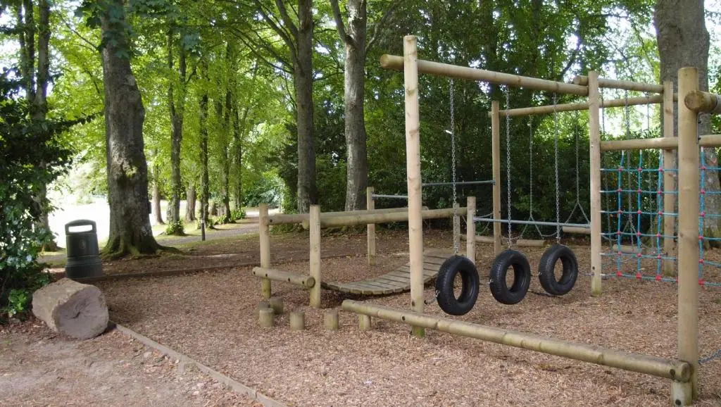 a park with a playground with logs and trees at Moat House 1 in Fort Augustus