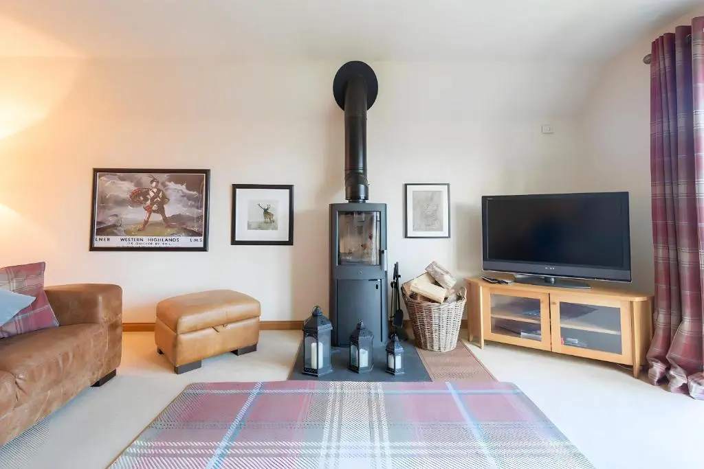 a living room with a couch and a flat screen tv at Carn Mhor Lodge in Aviemore