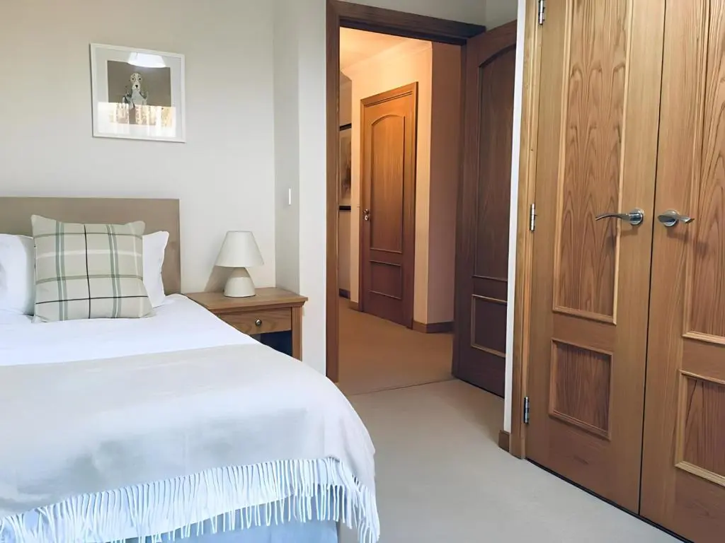 a bedroom with a white bed and a wooden door at Carn Mhor Lodge in Aviemore