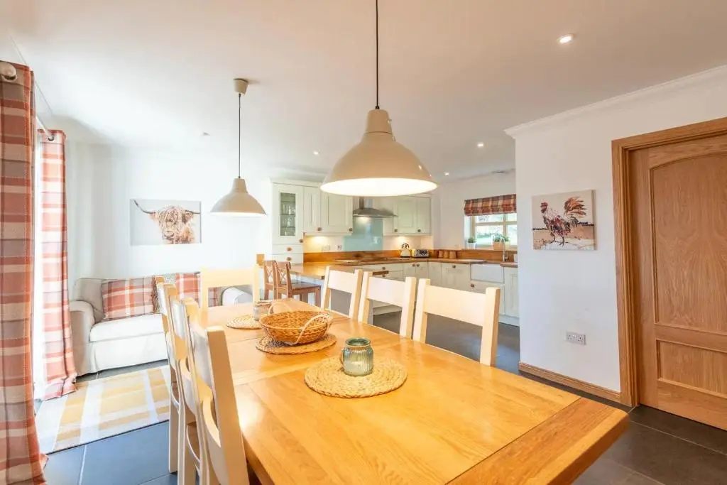 a kitchen and dining room with a wooden table and chairs at Carn Mhor Lodge in Aviemore