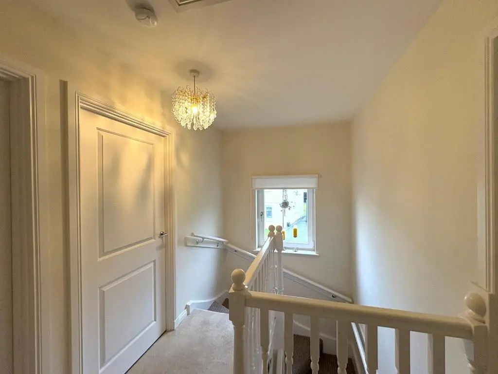 a hallway with a white door and a chandelier at Primrose View House in Inshes