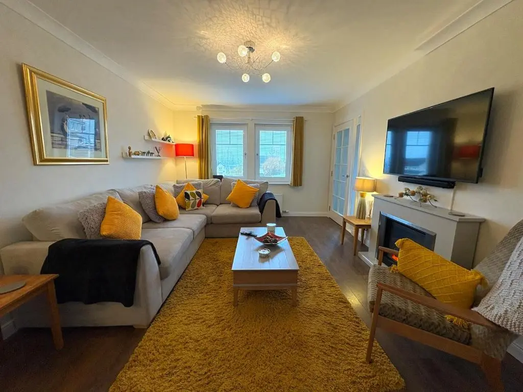 a living room with a couch and a tv at Primrose View House in Inshes