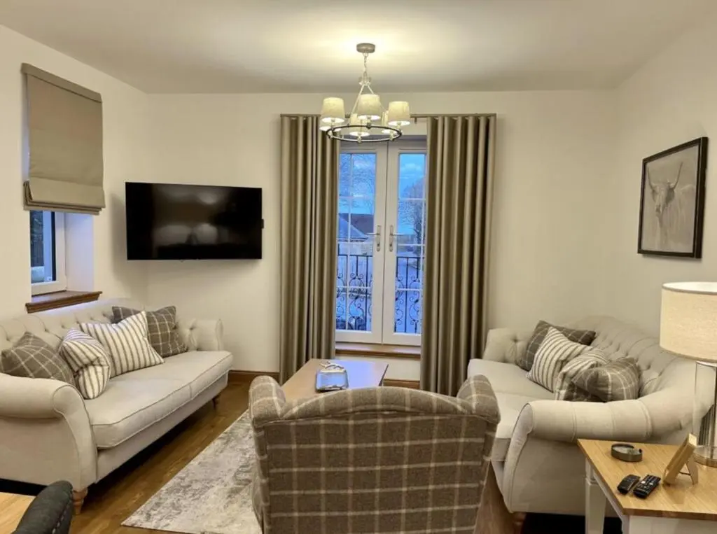 a living room with two couches and a tv at Royal Gardens Apartment 19 in Dornoch