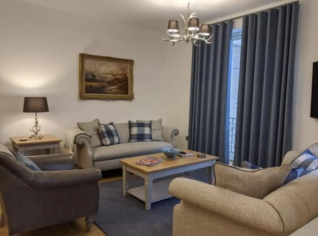 a living room with a couch and chairs and a table at Royal Gardens Apartment 2 in Dornoch