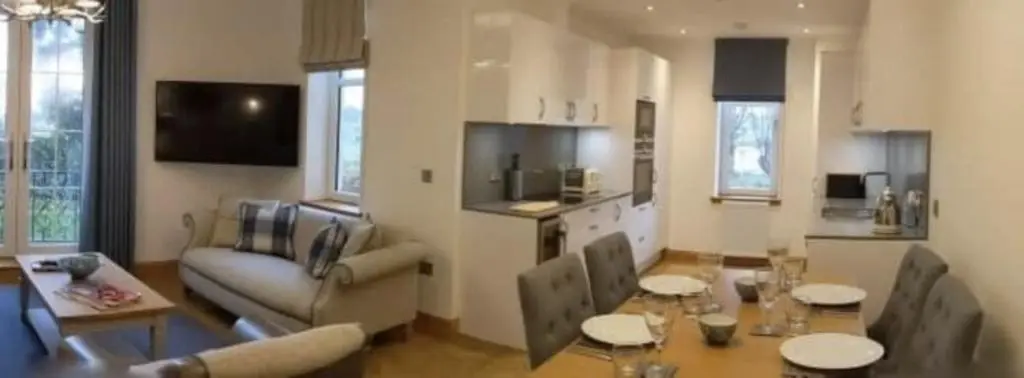 a living room with a couch and a table and a kitchen at Royal Gardens Apartment 2 in Dornoch