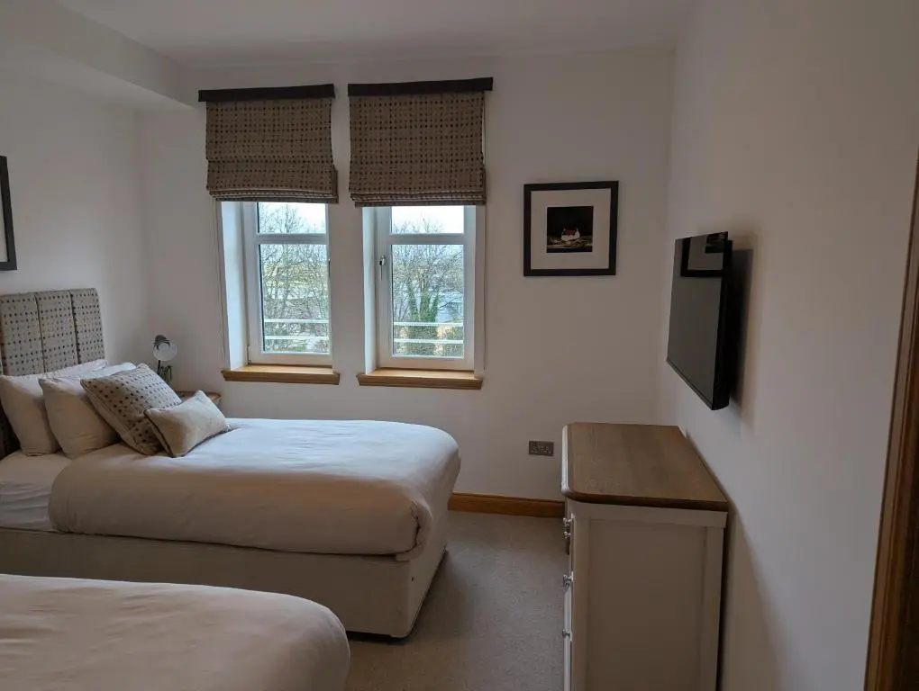 a bedroom with two beds and a television in it at Royal Gardens Apartment 11 in Dornoch
