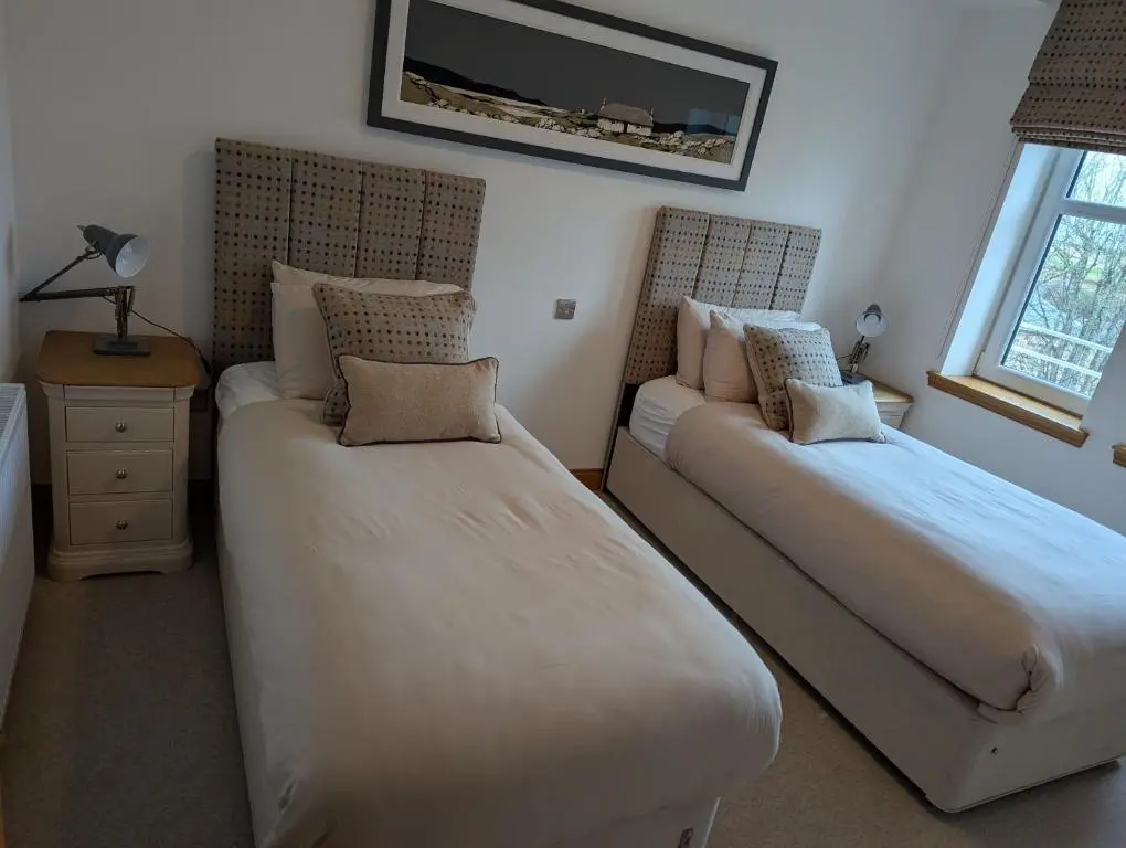 a bedroom with two beds and a window at Royal Gardens Apartment 11 in Dornoch