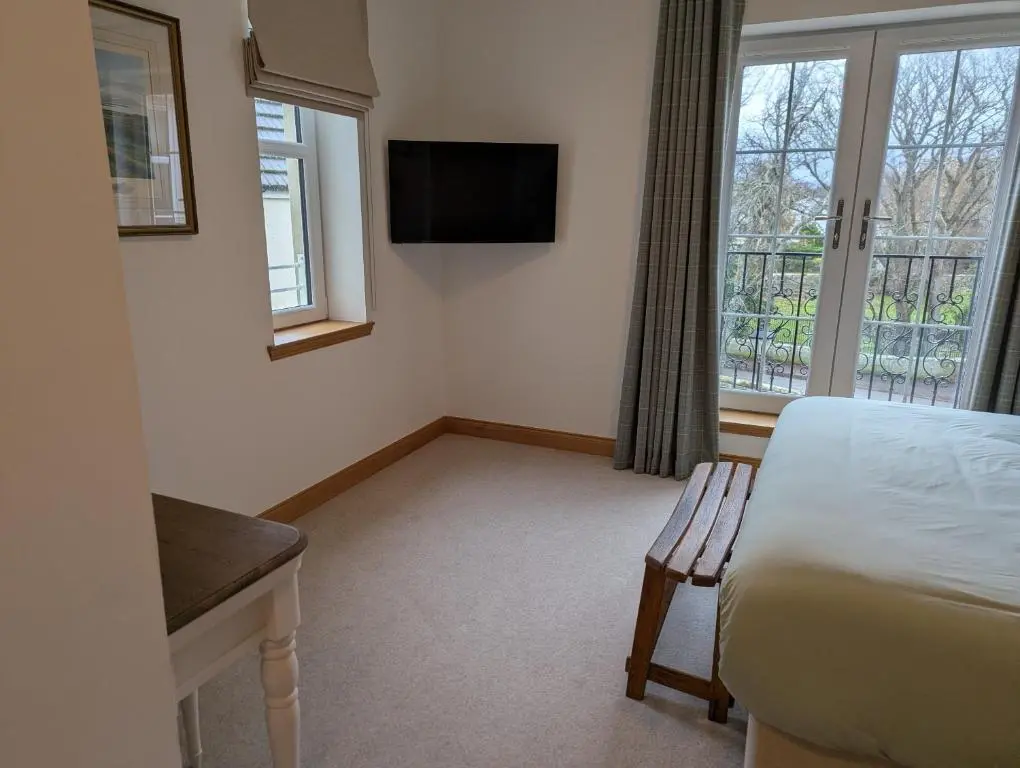 a hotel room with a bed and a television at Royal Gardens Apartment 11 in Dornoch