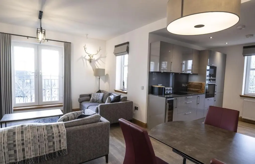 a living room with a dining table and a kitchen at Royal Gardens Apartment 10 in Dornoch