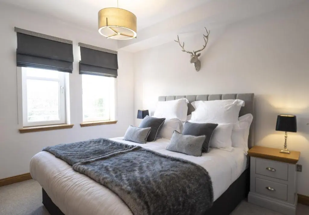 a bedroom with a large bed with white sheets and pillows at Royal Gardens Apartment 10 in Dornoch