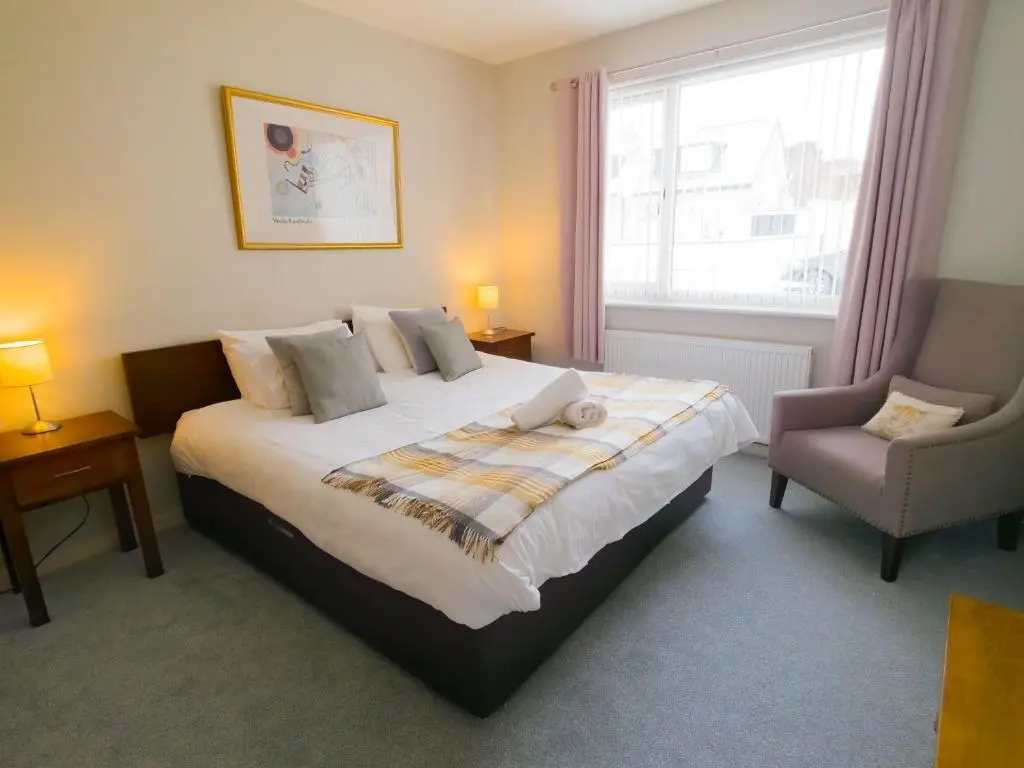 a bedroom with a large bed and a chair at Loramore in Aviemore