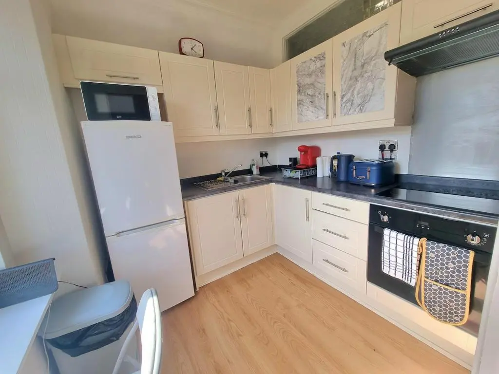 a kitchen with white cabinets and a white refrigerator at 2 bedroom flat- 5 minutes walk from city centre in Inverness