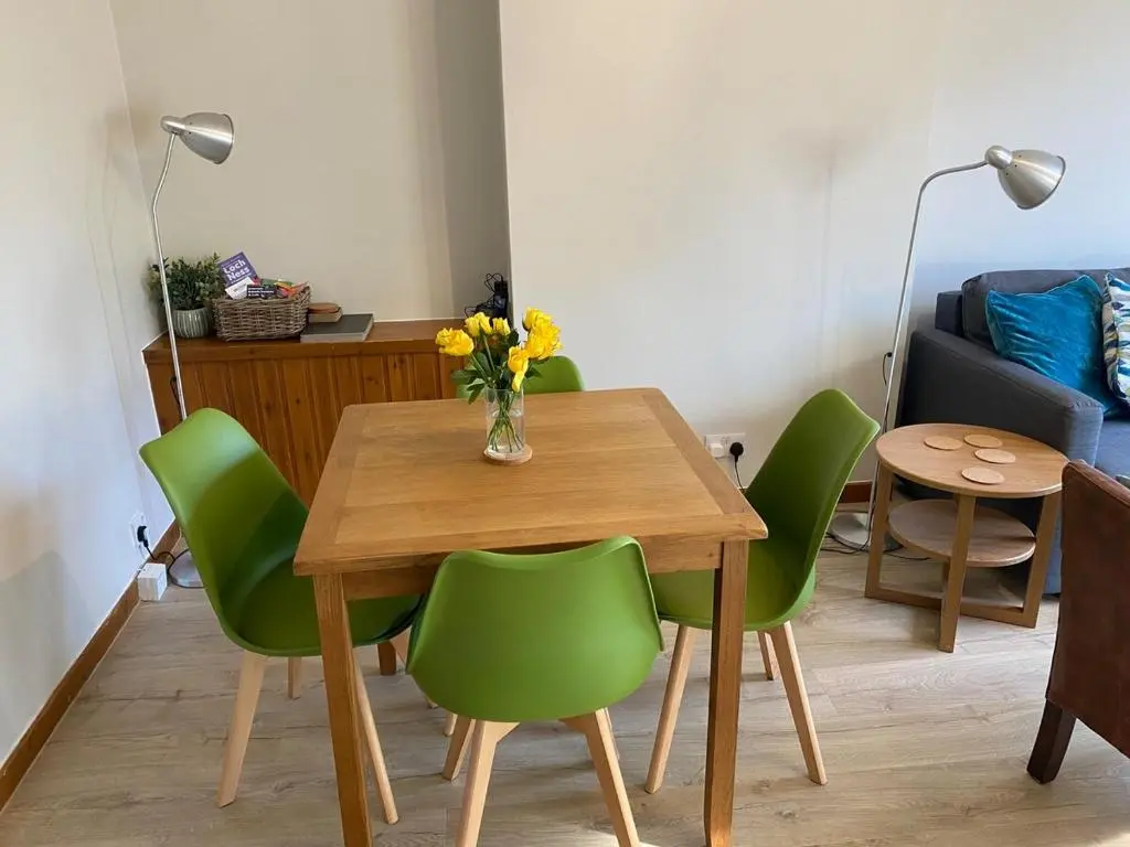 a dining room table with green chairs and a vase of flowers at Highland haven, free parking on driveway, near Raigmore Hospital in Inshes