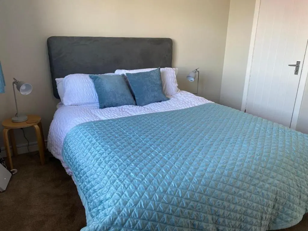 a bedroom with a large bed with a blue comforter at Highland haven, free parking on driveway, near Raigmore Hospital in Inshes