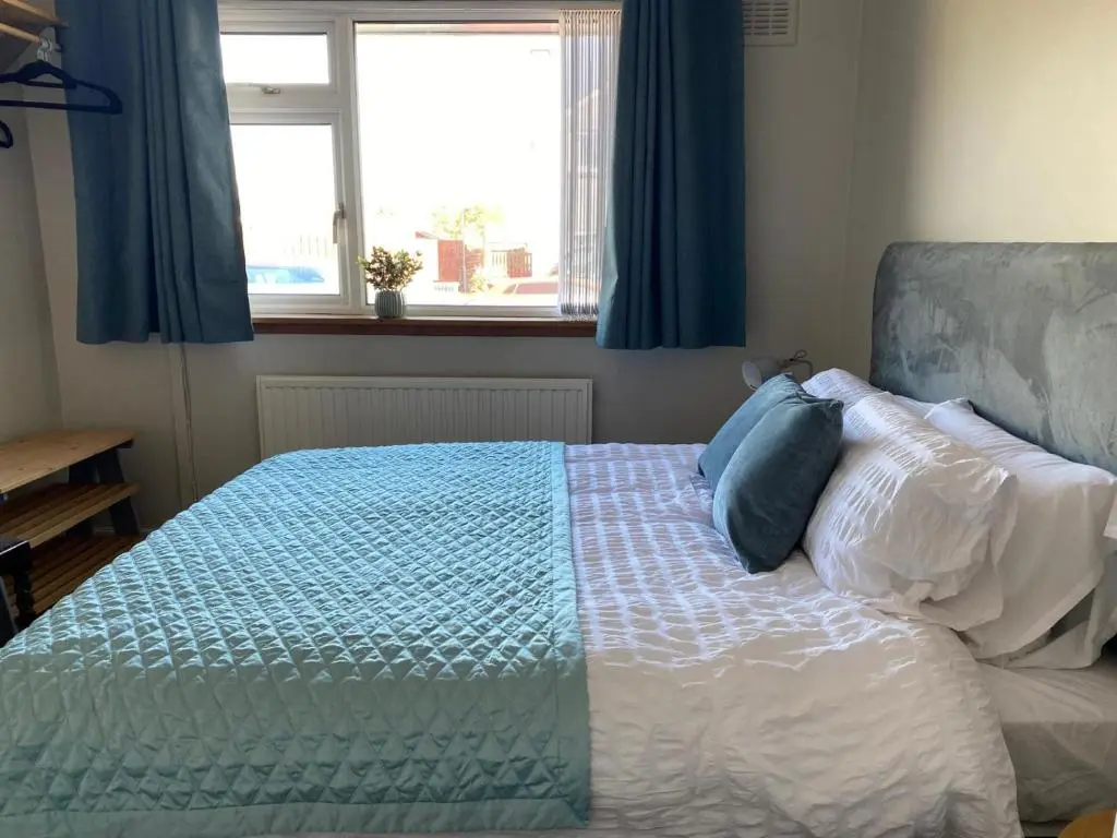 a bedroom with a bed with blue curtains and a window at Highland haven, free parking on driveway, near Raigmore Hospital in Inshes