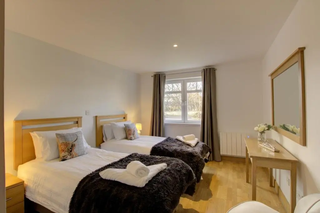 a hotel room with two beds and a window at No8 The Links Apartment, Brora in Brora