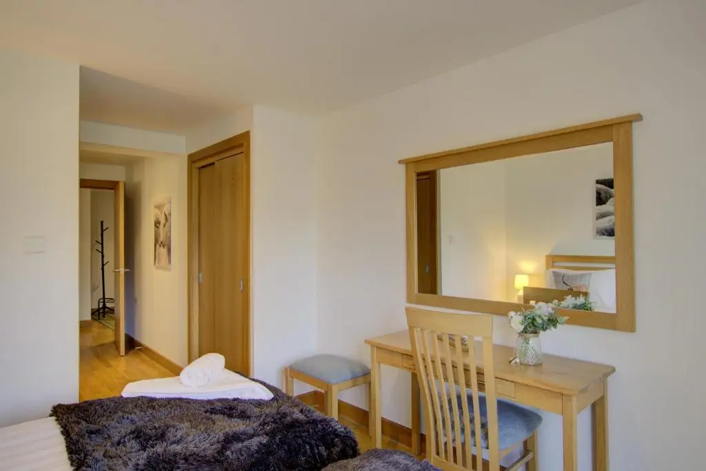 a room with a table and a chair and a mirror at No8 The Links Apartment, Brora in Brora