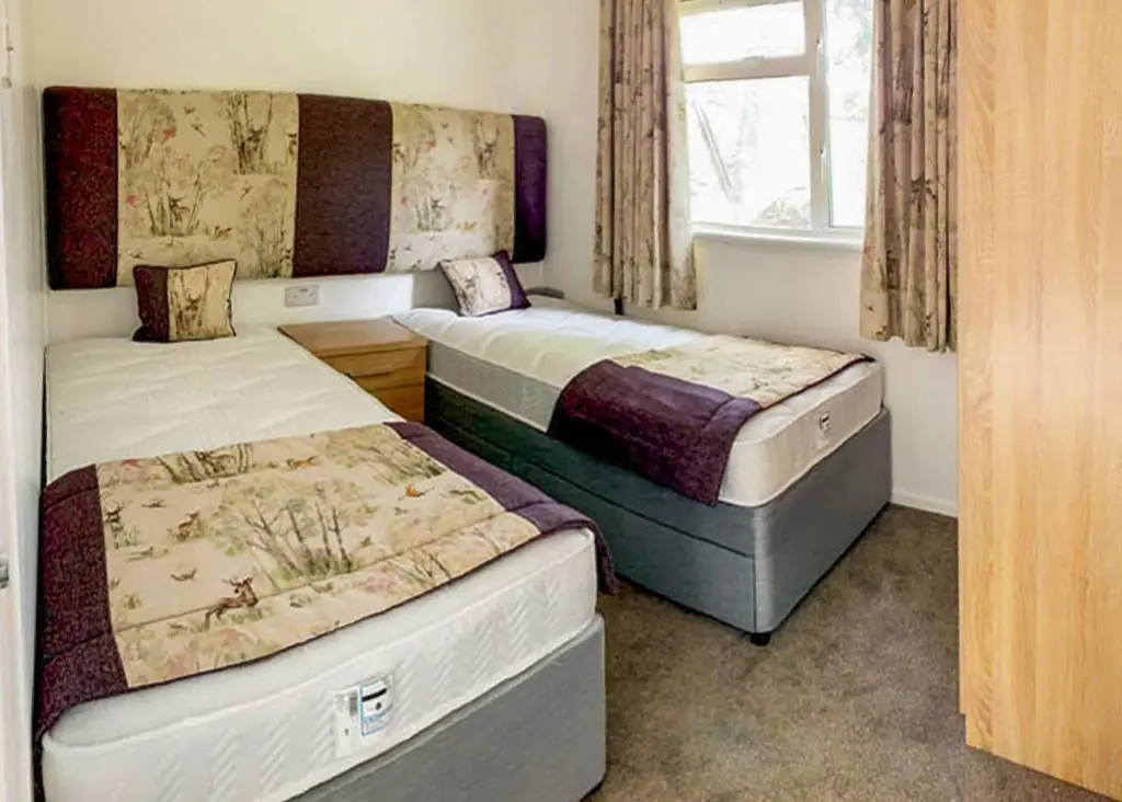 two beds sitting in a room with a window at Calvine Holiday Park in Pitlochry