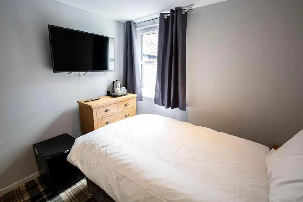 a bedroom with a bed and a television on the wall at Crown Hotel & Bar in Inverness