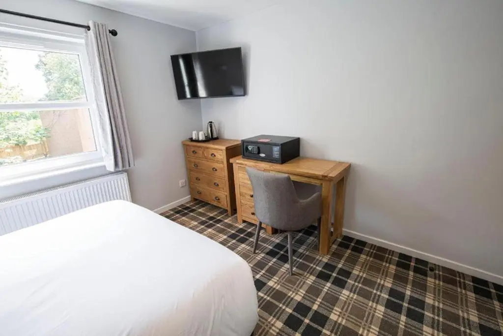 a bedroom with a bed and a desk with a television at Crown Hotel & Bar in Inverness