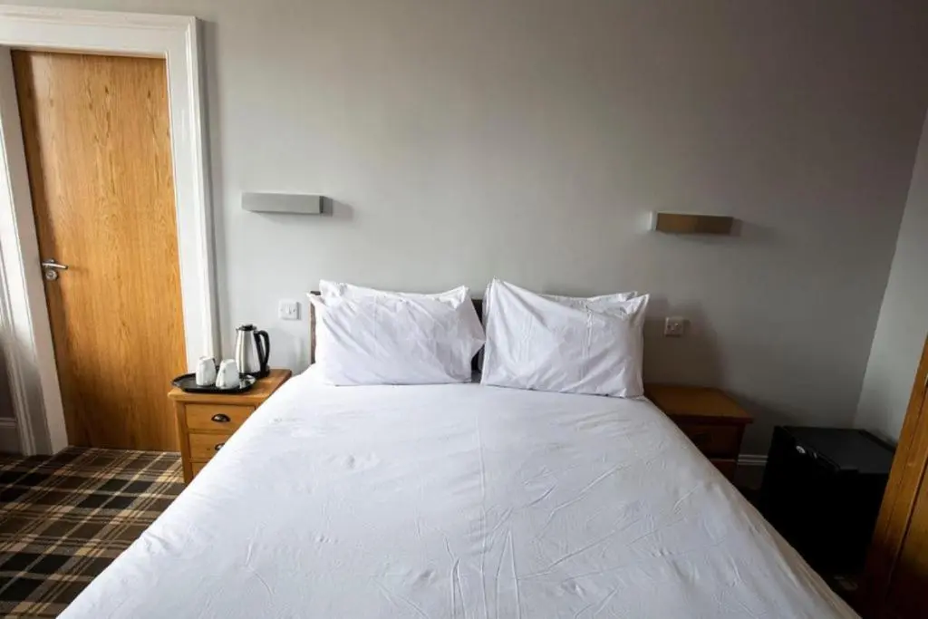 a bedroom with a white bed with two pillows at Crown Hotel & Bar in Inverness