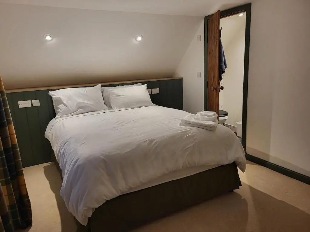 a bedroom with a large bed with white sheets and pillows at Gardeners Cottage