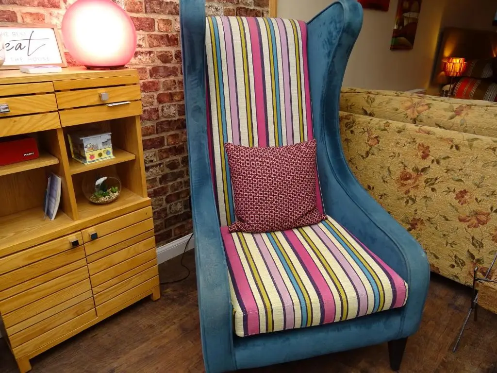 a blue chair with a colorful striped pillow on it at 'Le Studio' in Inverness