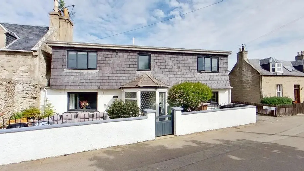 a house with a white fence in front of it at Bluebell Cottage in Nairn