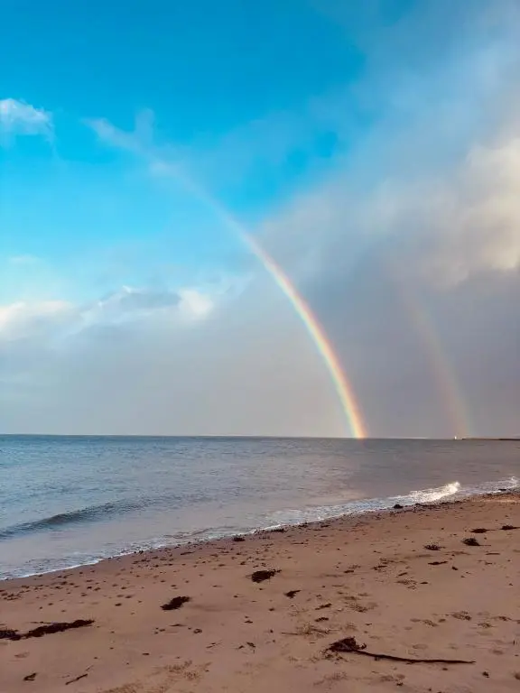 a rainbow over the beach with the ocean at Bluebell Cottage in Nairn