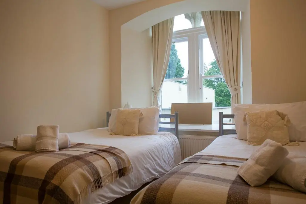 two beds in a room with a window at Old School Apartments Highland Club in Fort Augustus