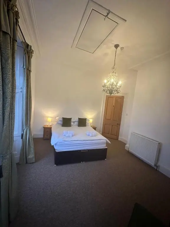 a bedroom with a bed and a chandelier at Auld Bank House in Braemar