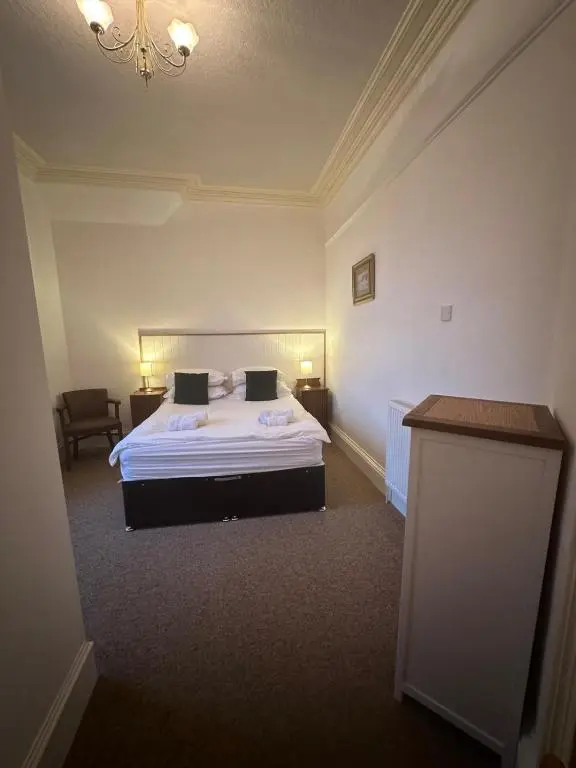 a hotel room with a bed and a chandelier at Auld Bank House in Braemar