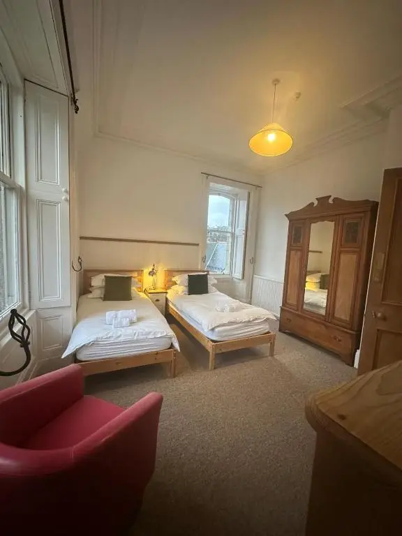 a room with two beds and a chair in it at Auld Bank House in Braemar