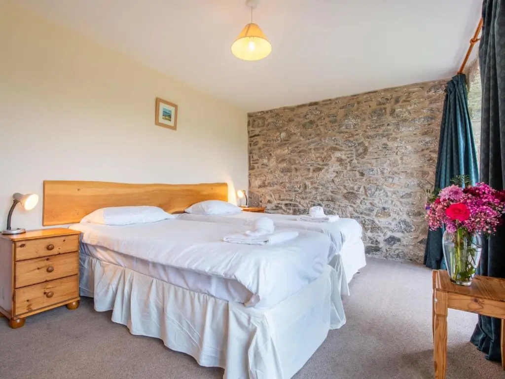 two beds in a hotel room with flowers on a table at Holiday Home Corrimony View by Interhome in Drumnadrochit
